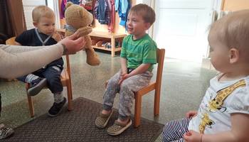 Die Erzieherin zeigt einem kleinen Jungen einen Teddybär
